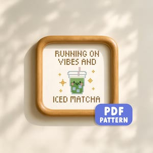 May include: A framed cross-stitch design with the text "RUNNING ON VIBES AND ICED MATCHA." The design features a green iced matcha drink with a smiling face, surrounded by gold star accents. A blue "PDF PATTERN" button is in the lower right corner.