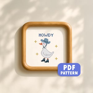 May include: A framed cross-stitch pattern featuring a white goose wearing a blue cowboy hat and boots. The word "HOWDY" is stitched above the goose, with gold crosses around the image. A blue "PDF PATTERN" button is in the lower right corner.