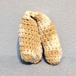 May include: Two crocheted beige and white finger puppets. The puppets are shaped like a pair of hands with fingers.