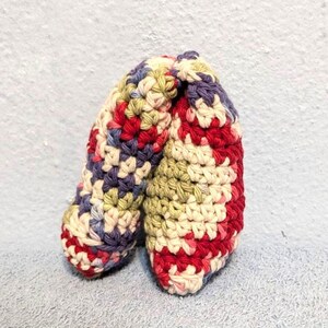 May include: A crocheted fortune cookie with a red, white, green, and purple color scheme.