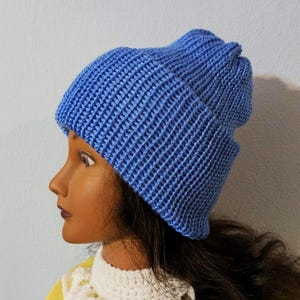May include: A blue knitted beanie hat. The hat is made of a ribbed knit fabric and has a folded brim. The hat is a solid light blue color. The hat is shown on a mannequin head.