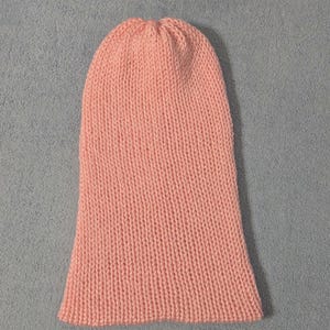 May include: A light peach-colored knitted beanie hat. The hat is made of a soft, textured yarn and has a close-fitting design. The hat is a solid color and is suitable for cold weather.