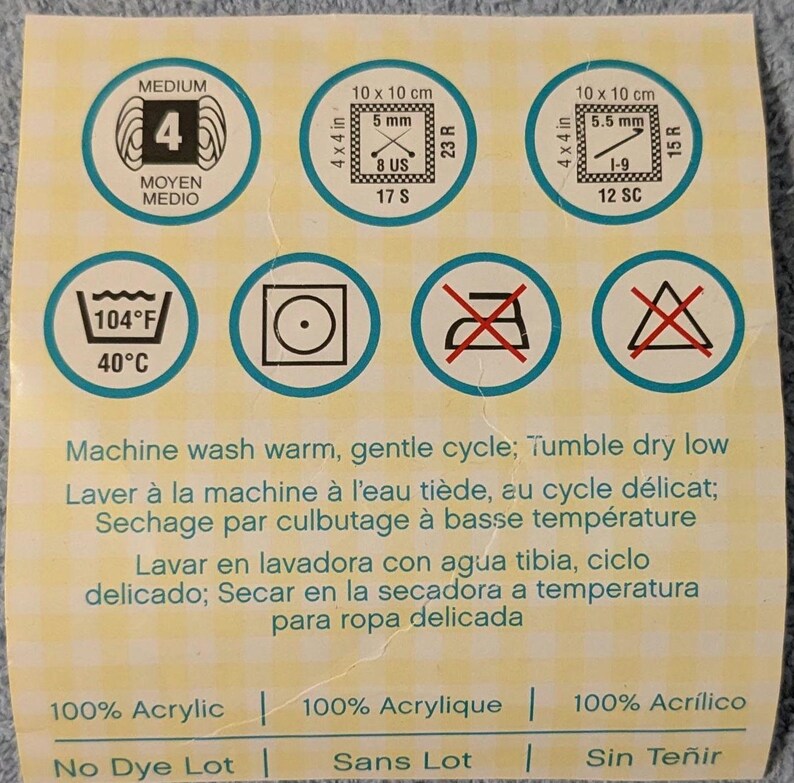 May include: A label with circular icons indicating yarn care instructions. Includes washing, drying, and material information. The label also shows yarn weight and gauge details, with measurements in inches and US sizes.