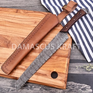 May include: A Damascus Kraft bread knife with a patterned blade and a wooden handle, resting on a wooden cutting board. The knife is accompanied by a brown leather sheath. The text "DAMASCUS KRAFT" is visible on the cutting board.