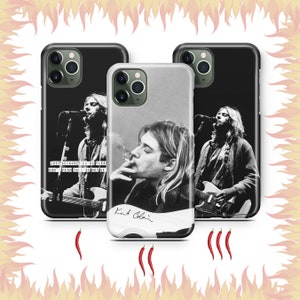 Puede incluir: Tres fundas de teléfono en blanco y negro con imágenes de Kurt Cobain. La primera funda muestra a Cobain tocando la guitarra. La segunda funda muestra a Cobain fumando un cigarrillo. La tercera funda muestra a Cobain tocando la guitarra con el texto "Just because you're paranoid doesn't mean they're not after you".