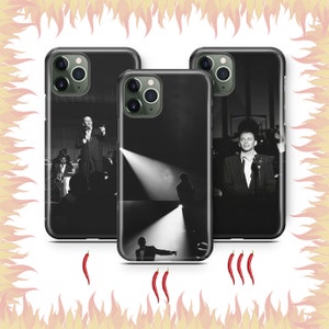 May include: Three black phone cases with different images. The first case features a man in a suit and tie speaking into a microphone. The second case features a man in a suit and tie standing on a stage with a spotlight shining on him. The third case features a man in a suit and tie standing on a stage with a spotlight shining on him.