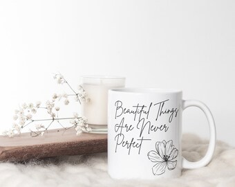 May include: White ceramic mug with a black floral design and the text "Beautiful Things Are Never Perfect".