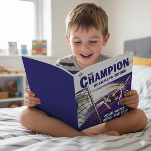 Może przedstawiać: Dziecko czyta książkę z niebieską okładką. Książka zatytułowana "The Champion Millwall FC Edition" zawiera ilustrację piłkarską. Widoczny jest również tekst "Your Name Wins the Cup".