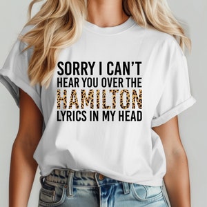 May include: White t-shirt with the text "Sorry I can't hear you over the HAMILTON lyrics in my head". The word "HAMILTON" is in leopard print.