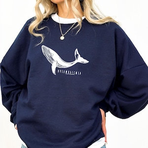 May include: A navy blue sweatshirt with a white whale graphic and the text "Overwhelmed" printed on the front.