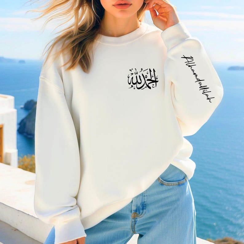 May include: White sweatshirt with black Arabic calligraphy on the front and the phrase "Alhamdulillah" on the sleeve.