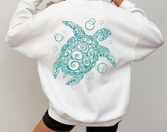 May include: White sweatshirt with a teal blue graphic of a stylized sea turtle with bubbles on the back.