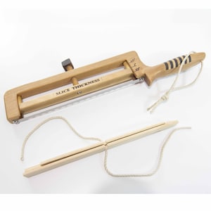 May include: A wooden tool for slicing vegetables with a rope and a wooden handle. The tool has a metal blade and a knob to adjust the slice thickness. The text "Slice Thickness" is printed on the tool.