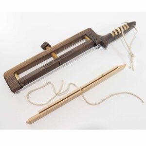 May include: A wooden slicing tool with a dark brown frame and a light brown handle. The tool has a screw mechanism for adjusting the slice thickness, with the text "SLICE THICKNESS" printed on the frame. A separate wooden piece is also included.