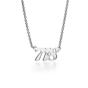 May include: A silver necklace with a pendant featuring the numbers 748 in a stylized font. A small diamond is set in the center of the number 4.