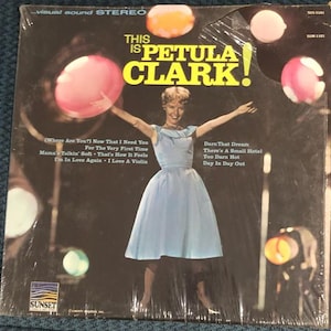Peut inclure: Pochette d'album vinyle vintage de Petula Clark en robe bleu clair. Le titre de l'album est "This Is Petula Clark!". La pochette présente un design rétro avec des accents circulaires colorés et le logo Sunset Records.