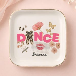 Peut inclure: Un vide-poche carré en céramique blanche avec un bord doré. Le centre présente le mot DANCE en lettres roses, avec des chaussons de danse remplaçant la lettre A. Les motifs incluent des papillons, des fleurs, des notes de musique et le nom Brianna.