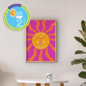 Puede incluir: Impresión artística enmarcada con un sol sonriente y el texto "You Are My Sunshine". El sol es amarillo con rayos rosas y naranjas sobre un fondo rosa. Incluye una oferta de bonificación para fondo de pantalla móvil.