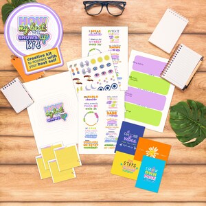 Puede incluir: Una colección de artículos de papelería, que incluyen cuadernos, pegatinas y tarjetas, dispuestos sobre una superficie de madera. Los artículos presentan diseños coloridos y frases motivadoras. El kit incluye una pegatina redonda con el texto "HOW my best self SHOWS up KIT".