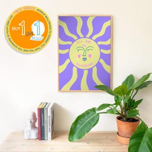 Puede incluir: Un cuadro enmarcado con un sol estilizado y el texto "You Are my Sunshine". El diseño del sol tiene una cara amarilla con corazones rosas y un fondo morado. Una oferta de bonificación es visible.