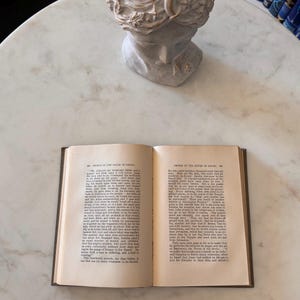May include: An open book with text, titled "Prince of the House of David," rests on a marble surface. A classical bust is in the background. The book's pages are aged, with visible text.