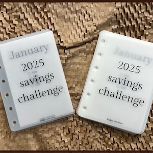 May include: Two white plastic sheets with holes on the left side. The sheets have the text "January 2025 savings challenge" printed on them.