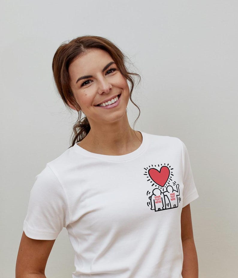 May include: White t-shirt with a red heart and two figures holding hands. The figures have the text "YOUR TEXT HERE" written on them.