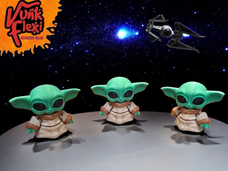 Może przedstawiać: Trzy zielone i brązowe figurki popularnej postaci fikcyjnej z franczyzy Star Wars. Figurki stoją na szarym tle na czarnym tle z białymi gwiazdami.