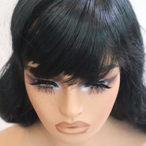 May include: A black wig with long, straight hair and blunt bangs. The wig is styled with a center part and has a natural-looking finish.