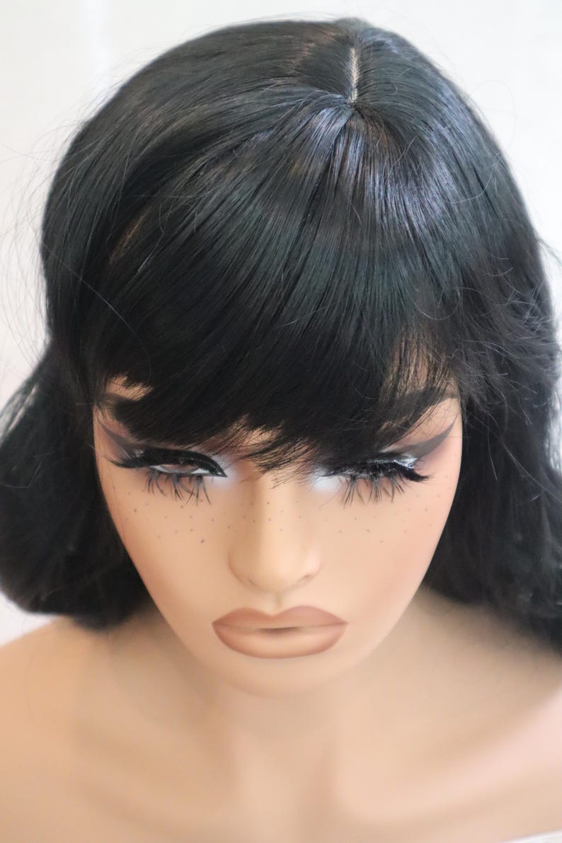 May include: A black wig with long, straight hair and blunt bangs. The wig is styled with a center part and has a natural-looking finish.