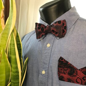 Könnte beinhalten: Ein blaues Hemd mit Knöpfen, einer schwarzen und roten Fliege und einem passenden Einstecktuch. Die Fliege und das Einstecktuch haben ein Paisley-Muster.