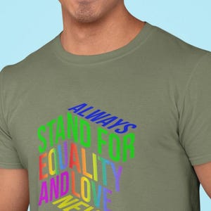 May include: Olive green t-shirt with the text "ALWAYS STAND FOR EQUALITY AND LOVE NEVER HATE" in a rainbow of colors. The text is in a 3D style, creating a bold and eye-catching design. The shirt is a casual wear item.