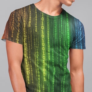 Peut inclure: Un t-shirt à manches courtes avec un motif vibrant et coloré. Le t-shirt présente un motif de type matrice de code binaire tombant dans des tons de jaune, de vert et de bleu. Le motif couvre tout le t-shirt, créant un look audacieux et accrocheur.
