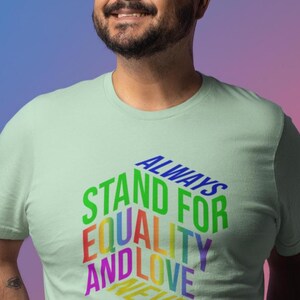 May include: A light green t-shirt with the words "ALWAYS STAND FOR EQUALITY AND LOVE NEVER HATE" in a rainbow of colors. The shirt is a crew neck style.