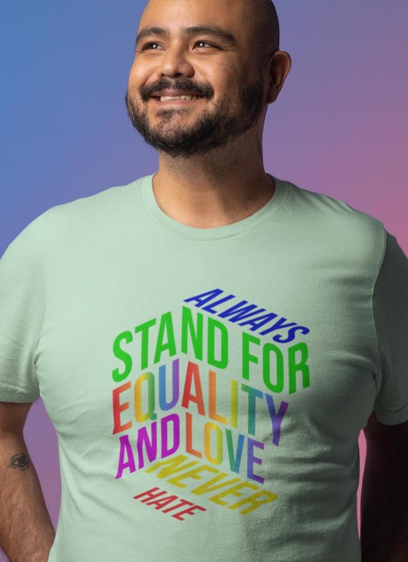 May include: A light green t-shirt with the words "ALWAYS STAND FOR EQUALITY AND LOVE NEVER HATE" in a rainbow of colors. The shirt is a crew neck style.