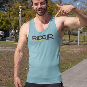 May include: Light blue tank top with the word "RIDGID" in black and a rainbow stripe underneath. The tank top is sleeveless and made of a soft material. The person is wearing black pants.