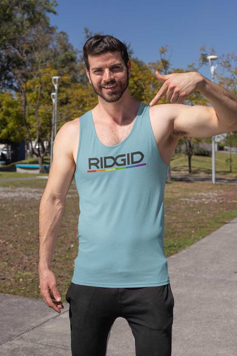 May include: Light blue tank top with the word "RIDGID" in black and a rainbow stripe underneath. The tank top is sleeveless and made of a soft material. The person is wearing black pants.