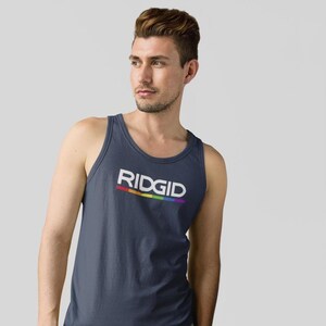 May include: Navy blue tank top with the word "RIDGID" in white block letters. A rainbow-colored stripe underlines the text. The tank top is a sleeveless shirt made of a soft material.