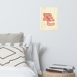 K&ouml;nnte beinhalten: Ein gelber und wei&szlig;er gestreifter Hintergrund mit den Buchstaben "BC" in Rot und Gold. Ein roter Adler fliegt &uuml;ber den Buchstaben.