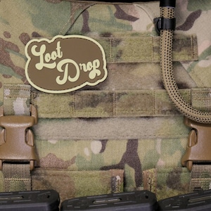 May include: A brown and tan tactical vest with a brown patch that says "Loot Drop" in a retro font.