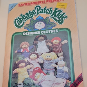 May include: A vintage Cabbage Patch Kids pattern book featuring a green and white logo with the text "Designer Clothes." The cover displays several dolls in various outfits. The book promises to make 25 outfits.