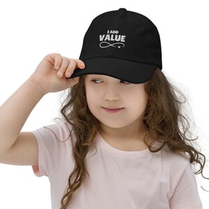 Puede incluir: Una gorra de béisbol negra con bordado blanco que dice "I ADD VALUE" con un símbolo de infinito y un corazón.