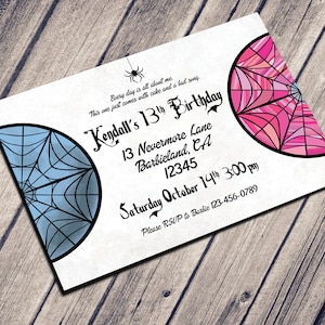 May include: A white invitation with a pink and blue spiderweb design. The text reads "Kendall's 13th Birthday" with the date and time of the party. The invitation is on a wooden background.