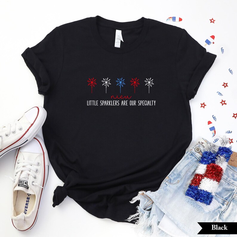 May include: Black t-shirt with a red, white, and blue firework design and the text "Little Sparklers Are Our Specialty".
