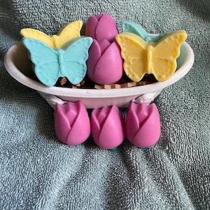 May include: A set of five handmade soap bars in the shape of tulips and butterflies. The tulips are pink and the butterflies are yellow and blue.