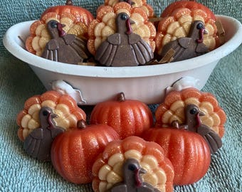 May include: A collection of small, molded wax figures shaped like turkeys and pumpkins. The turkeys feature brown bodies with glittery orange and gold fan-shaped tail feathers. The pumpkins are a vibrant, glittery orange color.