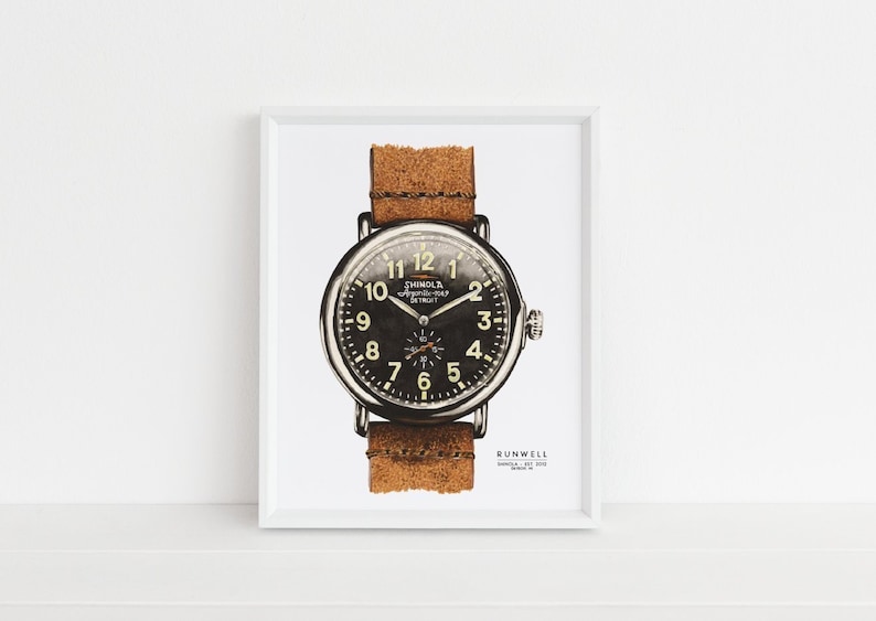 Puede incluir: Una impresi&oacute;n enmarcada en blanco de una ilustraci&oacute;n en blanco y negro de un reloj Shinola con una correa de cuero marr&oacute;n. La esfera del reloj tiene n&uacute;meros y manecillas blancos. El texto "Shinola Detroit" est&aacute; impreso en la esfera del reloj. El texto "Runwell" est&aacute; impreso debajo del reloj.