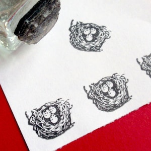 May include: A sheet of white paper with four black and white illustrations of bird nests with eggs. The nests are drawn in a simple, stylized manner.