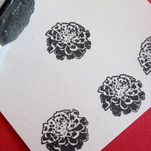 May include: Four black and white marigold flower stamps on a white card. The stamps are arranged in a grid pattern.