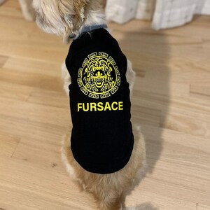 Black Dog shirt with the word FURSACE printed on it in yellow. The face in the logo is of a dog, incorporating dog ears and a smiling expression. The T-Shirt is designed for dogs, playing on the designer fashion brand in a humorous way.